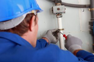 Plumber tightening a bracket on a water pipe